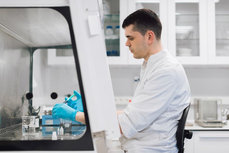 Researcher working in a biosafety cabinet in a pharmaceutical laboratory