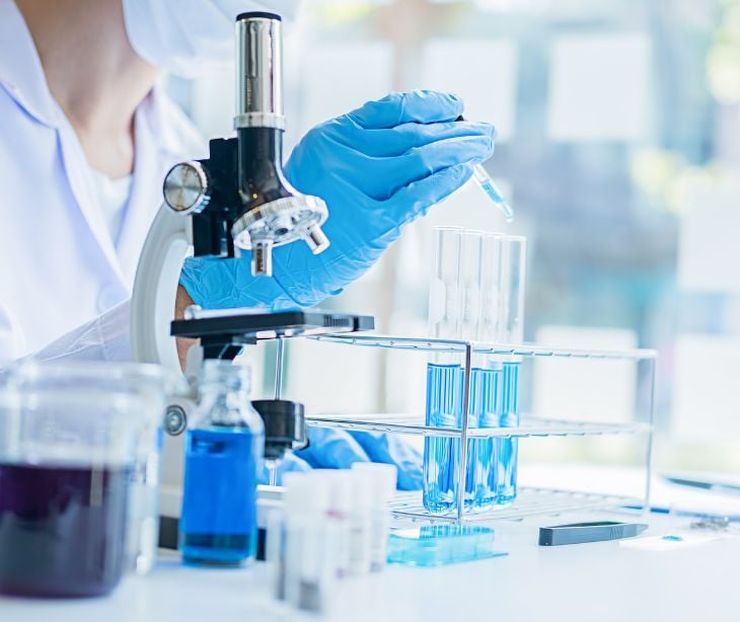 Scientist examining test tubes and microscope during gout clinical trial research