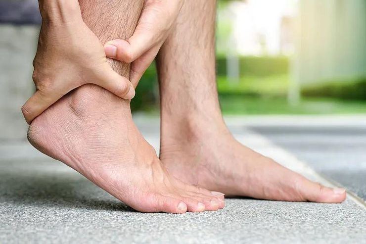 Man holding a painful swollen ankle outdoors