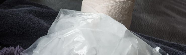 Ice pack made with crushed ice in a plastic bag resting on a bandaged, swollen foot at home