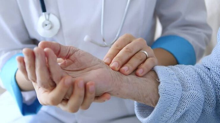 A clinician checking an older patient's wrist pulse during a cardiovascular health examination