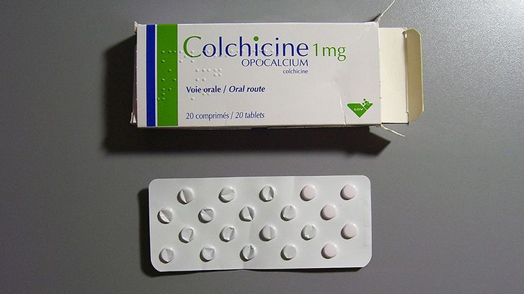Common gout flare medications including colchicine and anti-inflammatory pills in amber bottles on a kitchen table