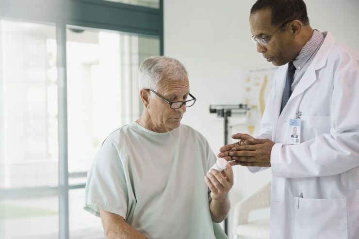 Doctor reviewing a medication bottle with an older patient during a clinic visit