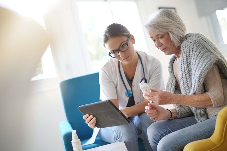 Clinician reviewing a medication bottle and treatment results with an older patient during an office visit