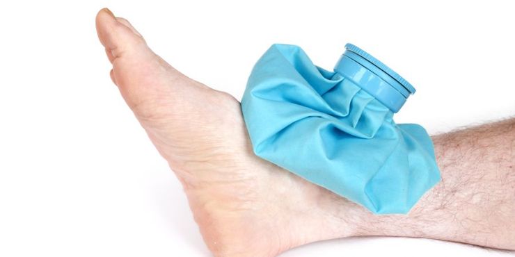 Gel ice pack wrapped in a thin kitchen towel resting on a swollen foot at home