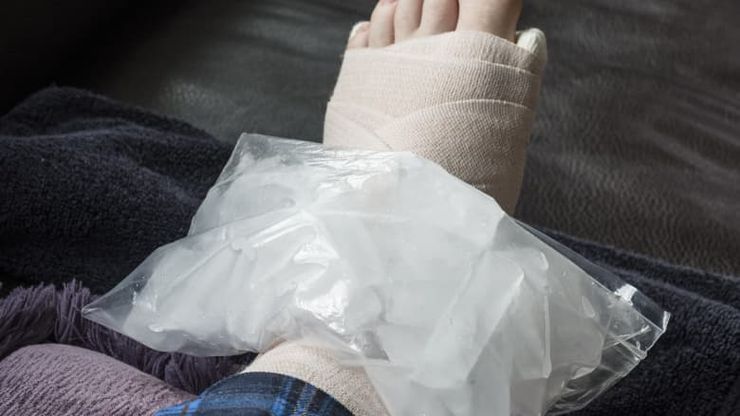 Ice pack wrapped in a towel resting on a swollen big toe at night