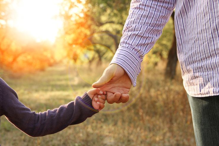A parent holding a young child’s hand, symbolizing the family history behind gout risk