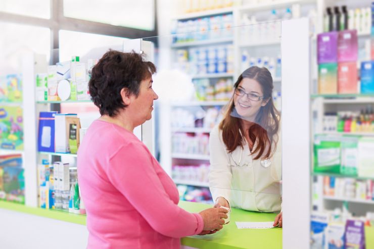 Pharmacist handing medication across the pharmacy counter during a consultation