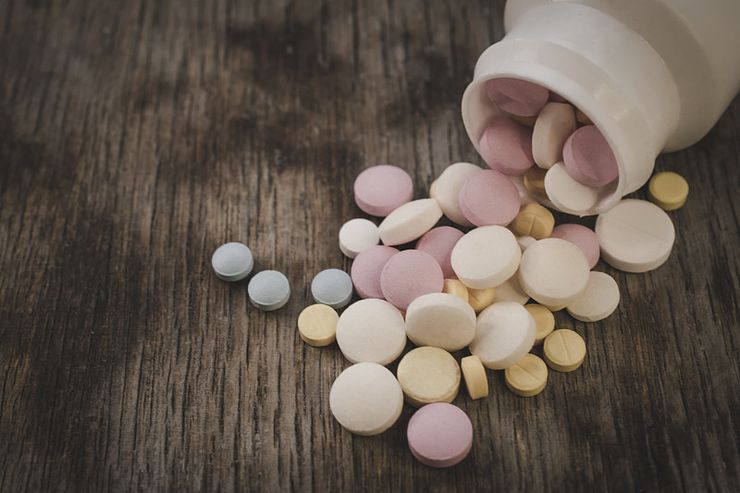 Ibuprofen and naproxen bottles with tablets next to a medication dosing instruction sheet