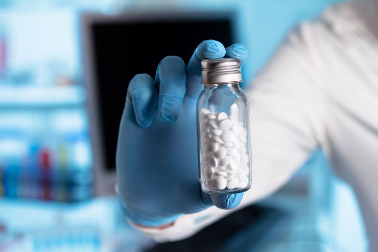 A pharmacist reviewing a medication chart and prescription bottle with a patient
