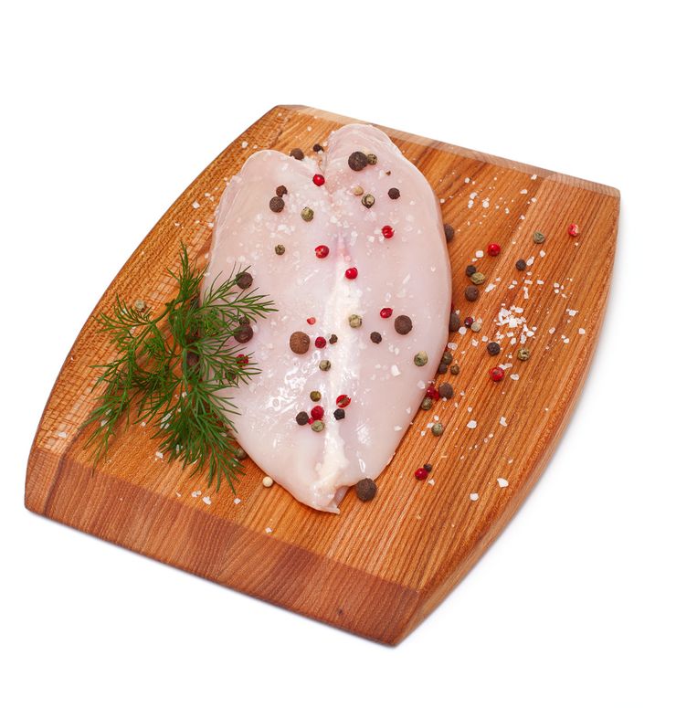 Raw skinless chicken breast on a cutting board with a knife