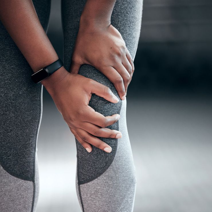 Person holding a swollen, painful knee with both hands