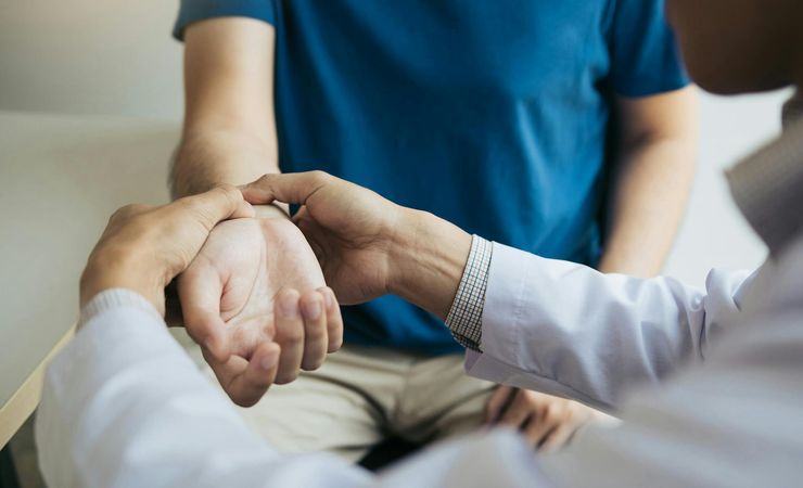 Doctor examining a patient's painful wrist during a clinic visit