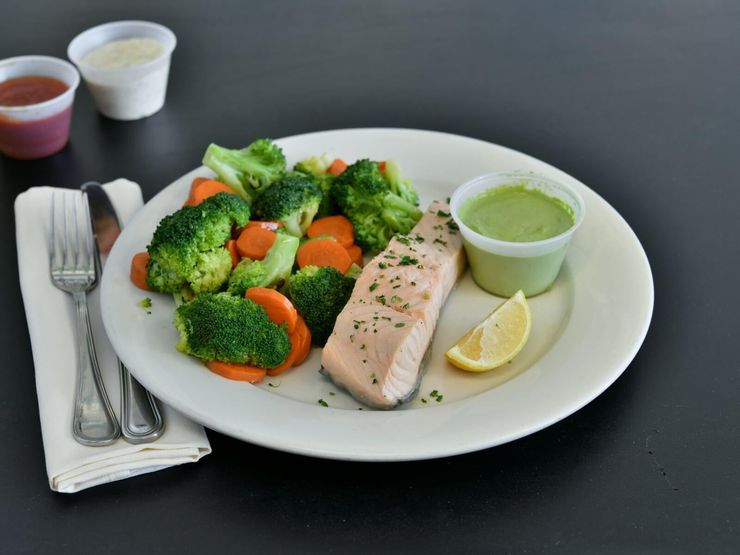 Poached salmon fillet served with steamed broccoli, carrots, and a lemon wedge