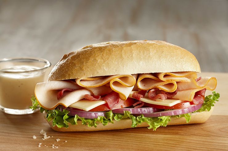 Deli turkey sandwich stacked with turkey breast slices, lettuce and tomato
